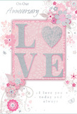Captured as if lying on a well-loved wooden desk in a Kentish Town home, this anniversary card offers a gentle yet heartfelt portrayal of enduring romance. The design blends soft pastel pinks and silvery greys, creating a cosy, intimate feel much like a quiet evening in with the lights low and the city hushed beyond Dartmouth Park. At the centre, the word LOVE rises from the card in soft, raised glitter, its letters edged with a subtle sparkle that catches the light without feeling showy. The O is transformed into a shimmering heart shape, textured in gleaming silver, becoming the focal point of the word and symbolising the emotional core of the message. Around this central motif, delicate blossoms unfurl in blush and mauve, their petals painted with an almost watercolour softness so that edges blur slightly, as though seen through a gentle haze. Fine, flowing lines suggest stems and vines, meandering gracefully across the card in a pattern that recalls the natural movement of a florist's hand when arranging a romantic bouquet for delivery along Fortess Road or toward Gospel Oak. Tiny flourishes - scattered petals, swirling curls, and discreet butterflies - add a sense of light motion, as if a soft breeze had just stirred the arrangement. The background is a velvety blush pink that sets off the silvery accents and makes the floral elements appear to float. In an understated, flowing script, the phrases On Our Anniversary and I love you today and always are written with gentle clarity, reinforcing the sincerity of the design. Altogether, the card feels like an English spring garden distilled into paper form - tender, thoughtful, and perfectly suited for commemorating a shared journey of love in and around Kentish Town.